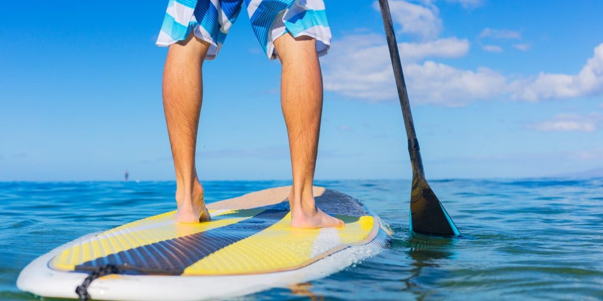 Young Attractive Mann on Stand Up Paddle Board, SUP, in the Blue Waters off Hawaii